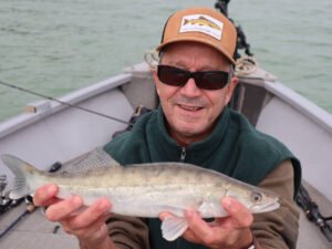 Un pêcheur sur un bateau au lac de la Ganguise qui montre un sandre.