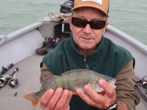 Un pêcheur sur un bateau au lac de la Ganguise qui montre une perche.